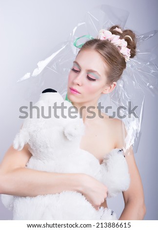 Girl with a toy bear in hands, beauty fantasy. Young woman with a gentle make-up and hairstyle, decorated with candy. Candy-girl package, candy makeup