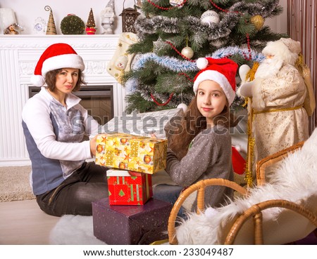 Mom and daughter with gifts under the Christmas tree. Family with gifts near a Christmas tree.