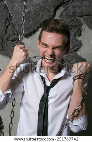 A man in a white shirt and tie breaks the chain teeth. Office worker breaks his chains