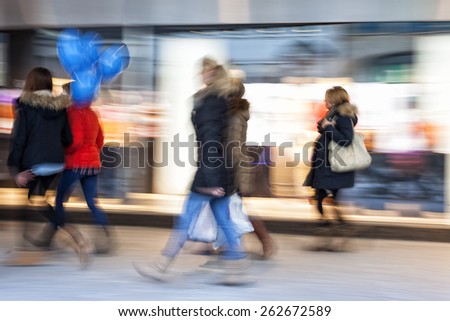 Shopper walking against shop window at dusk, zoom effect, motion blur
