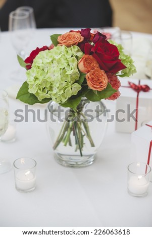 Glass Vase Full of Bright Roses and Other Flowers on White Table - Narrow Focus