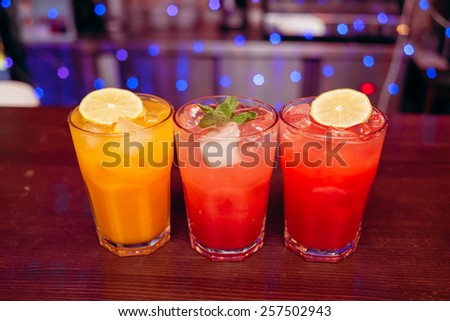 three colored bright cocktail with mint and lemon on the wooden bar counter