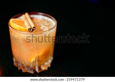 beautiful cocktail glass with cinnamon and orange on a dark wooden bar counter from above