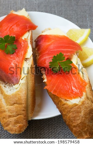 Slices of fish and white bread with butter on a white plate.