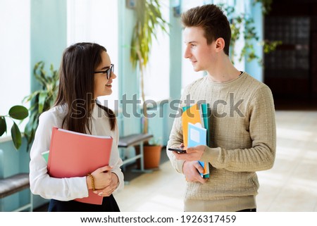 Two smiling students in love communicate during break holding learning materials afraid to express their feelings to one another Stock foto © 