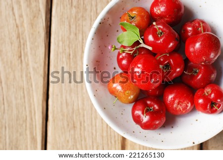 Small red fruit . Brazilian Acerola Fruit . small cherry in a bowl on wooden background.