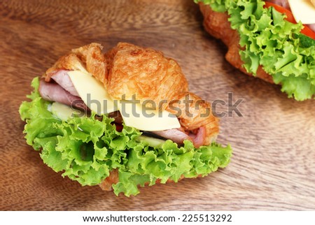 fresh croissant ham cheese sandwiches on wooden board.