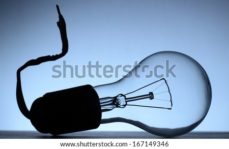Light bulb installed into disconnected lamp socket with torn wire in cool colors. Conceptual image representing for example idea not properly applied