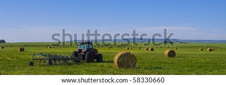 Alfalfa hay bales in a field with tractor in the Canadian prairie\'s, Alberta, Canada