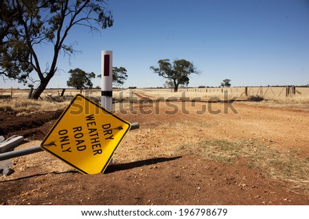Dry weather sign lies beside dry dusty road on a hot summer day.