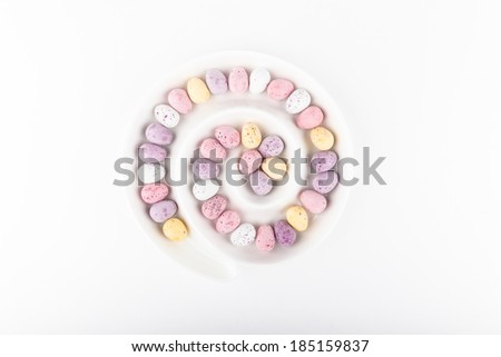 Mini easter eggs in white spiral dish on white background
