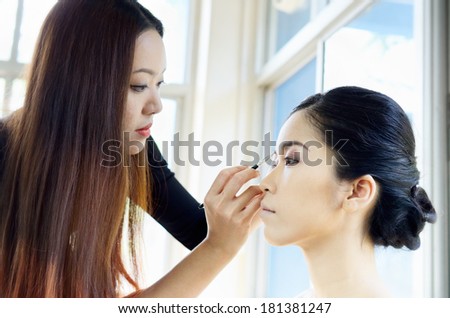 Asia woman applying makeup by makeup artist/Wedding makeup artist