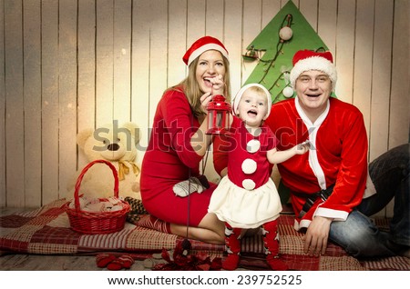 Happy family in Santa\'s cloth with snowman baby near Christmas tree and toys.  Father, mother and baby