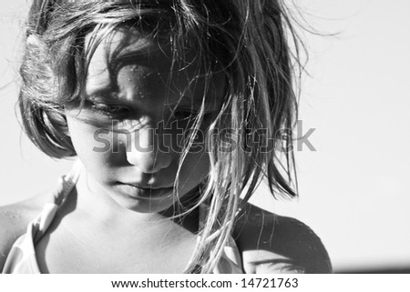 B&W photo of 6 year old girl looking down with a look of anger and frustration on her face