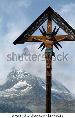 Wooden Cross framing the Matterhorn Switzerland with cloudy blue sky and snow in the background