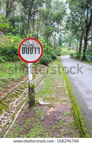 Slow down sign in the public park, Thai language.