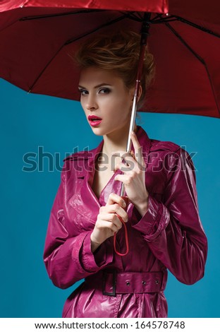 Young woman with red umbrella on blue