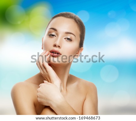 Beautiful girl on a background of a sea landscape. Sunny beach and blue sky. Clean and young skin.