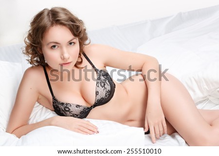 Girl in lingerie on the bed. Sexy brunette on white bed sheets. The morning sun in the bedroom.