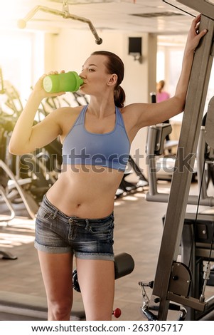 Sports girl drinks water in the gym after workout. Stained instagram.
