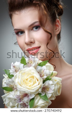 Young cute smiling woman with a bouquet of roses and orchids. The bride with a wedding bouquet.