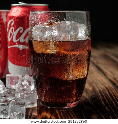 MINSK, BELARUS-MAY 22, 2015: Can and glass of Coca-Cola with ice on wooden background. Coca-Cola is a carbonated soft drink sold in stores, restaurants, and vending machines throughout the world.