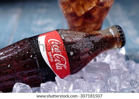 MINSK, BELARUS-AUGUST 16, 2015: Classic Bottle of Coca-Cola Zero on the ice over blue wooden background. Coca-Cola is a carbonated soft drink sold in stores and vending machines throughout the world.