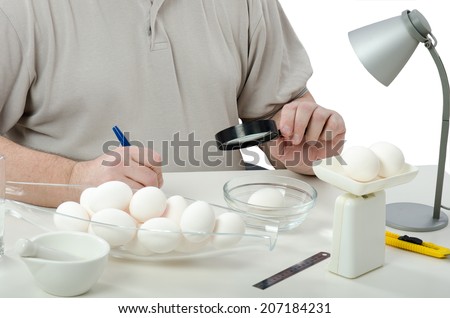 Quality control expert hands inspecting eggs in laboratory with magnifying glass