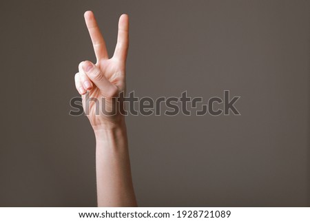 Similar – Image, Stock Photo Female palm with V-sign with rainbow bracelet