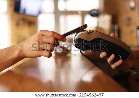 Image, Stock Photo Macro unknown hand giving terminal to visitor for mobile phone payment indoor. Client hand paying bill with smartphone in blurred background. Cropped shot hands making contactless transaction inside.