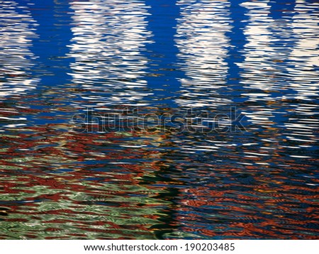 Red Blue white Color pattern shimmers and reflects in ripples of water making a psychedelic pattern.