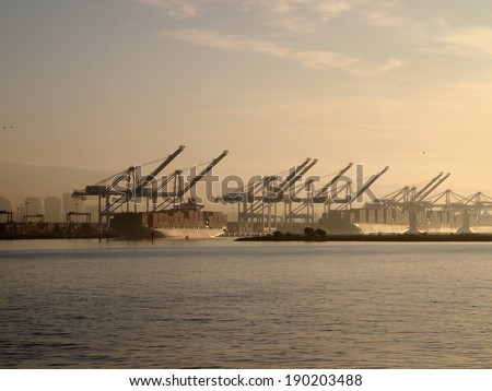 Cargo Boats for of crates rest under cranes in Oakland Harbor on a foggy day in California.