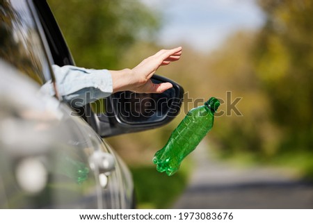 Close Up Of Driver In Car Dropping Trash Out Of Window On Country Road Foto stock © 