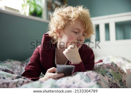 Unhappy Teenage Girl Lying On Bed At Home Withg Mobile Phone Being Bullied On Social Media Foto stock © 