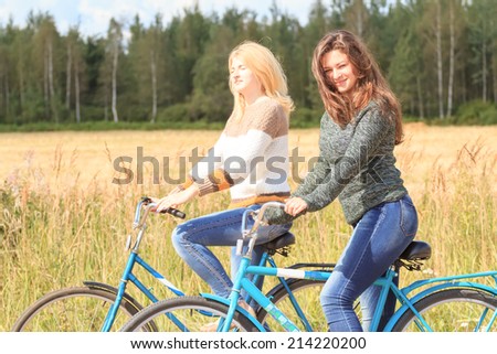 Two happy girls enjoying cycling in sunny day