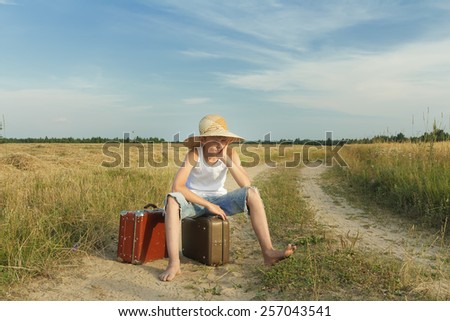 Teenage traveler waiting and sitting on a luggage