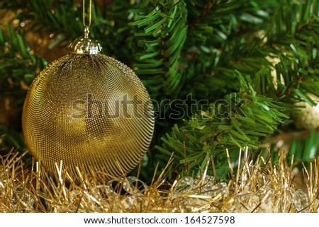 Horizontal image of the detail of golden decoration on the christmas tree with gold chain. Gold and green colours