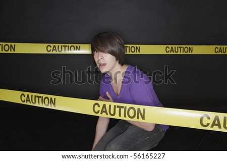 Young man crouching and cordoned off with tape