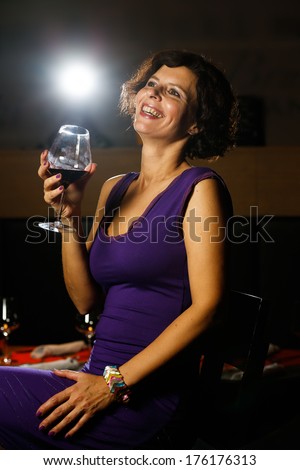 Beautiful lady in dress drinking wine and smiling in nightclub