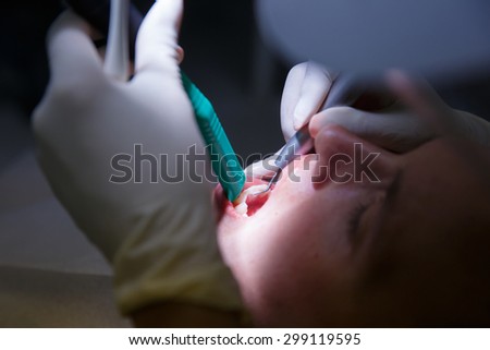 Patient at dentists office, getting soft-tissue probed and teeth cleaned of tartar and plaque
