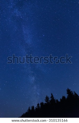 Beautiful, wide blue night sky with stars and visible Milky way galaxy, photographed on a mountain pasture. Astronomy, romantic, clear sky concept and background.