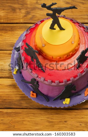 Fondant Cake on picnic table/Music  themed cake on picnic table. Vibrant colorful cake on wooden table. Holiday sweet food. Music cake. Dancer figure on top of cake.