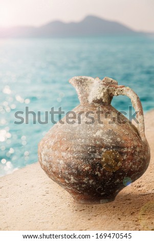 Ancient water jar/Old terracotta jar on stone table near seaside.