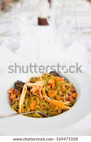 Pasta with crayfish in plate/Serving size of green fusilly pasta and seafood. Mussels and carrots mixed in pasta.