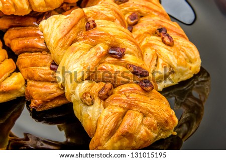 Some pastries filled by honey syrup and sprinkled by pecan nuts on black plate