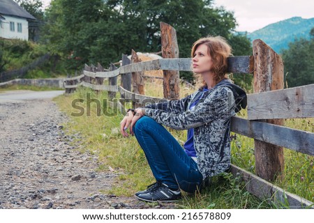 Portrait of a young girl sitting in front of fence