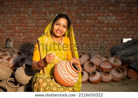 Portrait of happy traditional Indian woman potter artist painting and decorating design on clay pot for sale, handicraft, skill india. 商業照片 © 