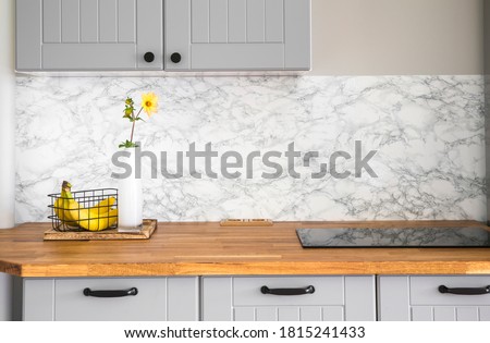 Modern minimal gray color kitchen with self adhesive fake marble imitation tape on wall, solid natural wood countertop with built in small stove.