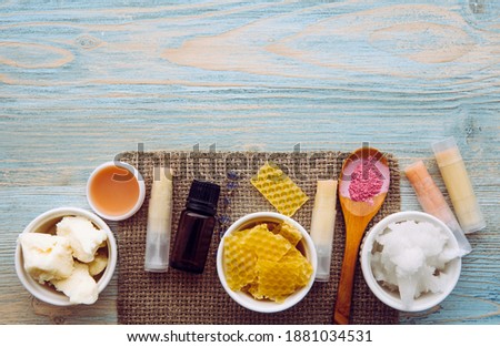 Ingredients for homemade lip balm: shea butter, essential oil, mineral color powder, beeswax, coconut oil. Homemade lip balm lipstick mixture. Lot of blank room for text.