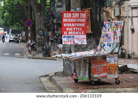 HANOI, VIETNAM - JUL 13, 2014: A newsstand with many daily newspapers on the sidewalk of a street in Hanoi capital. Vietnam has more than 600 state owned newspapers and media agencies.